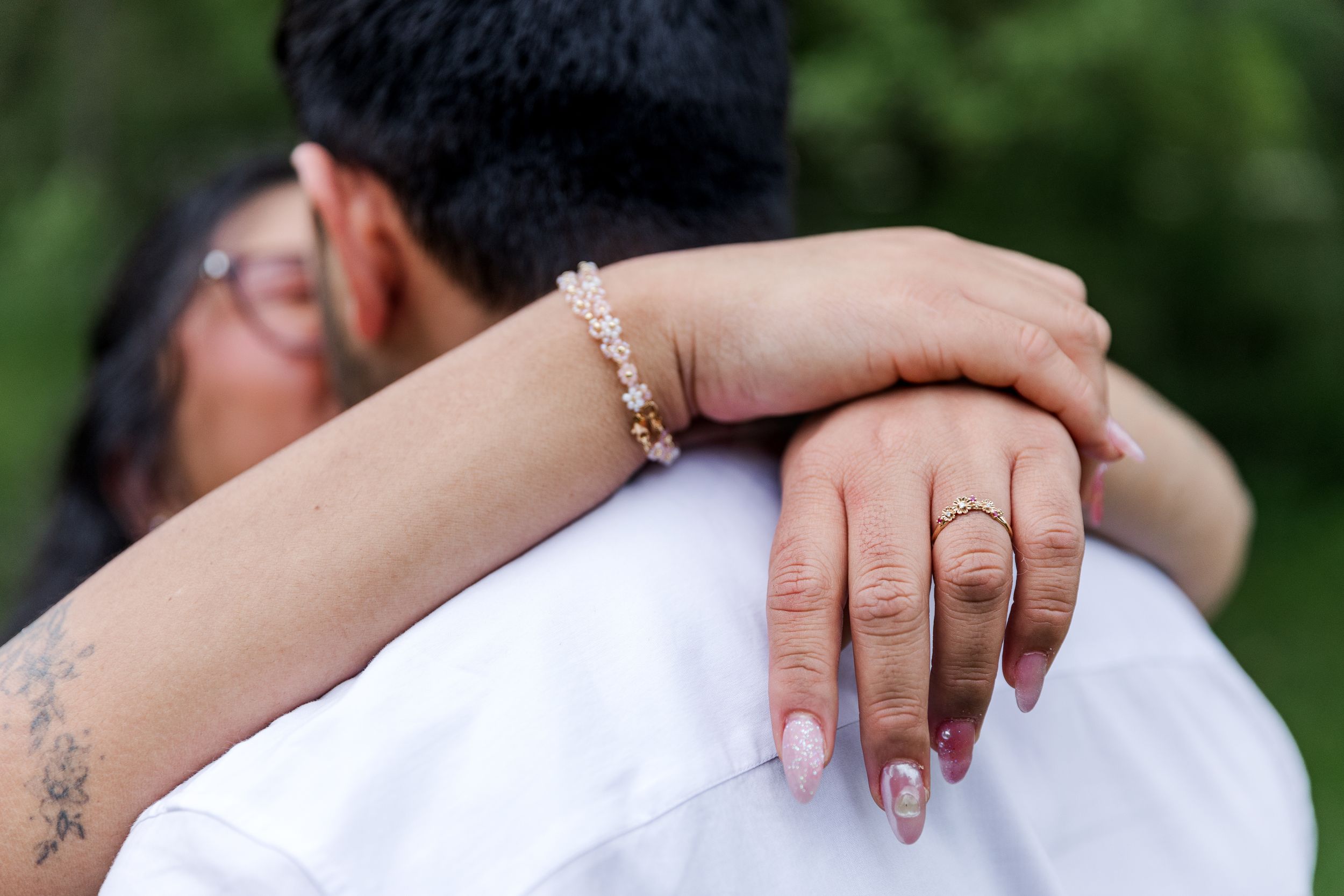 Close-up view of hands with wedding rings touching during an intimate outdoor wedding ceremony.