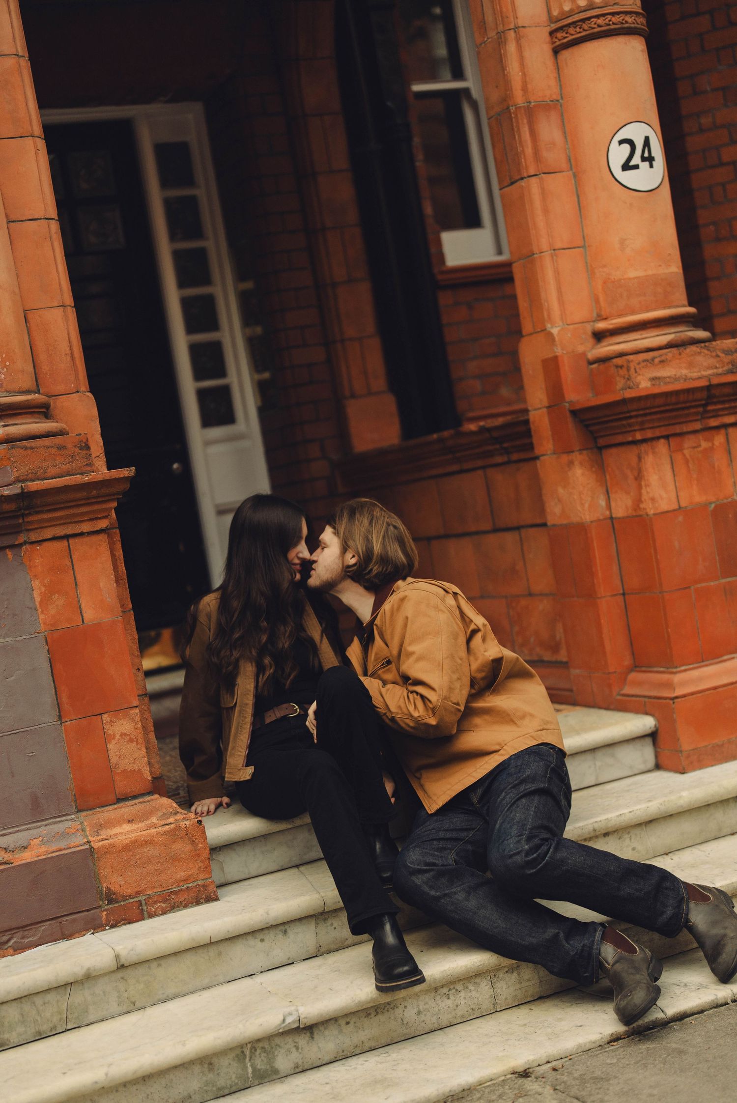 A couple sharing intimate moments on red brick building steps.