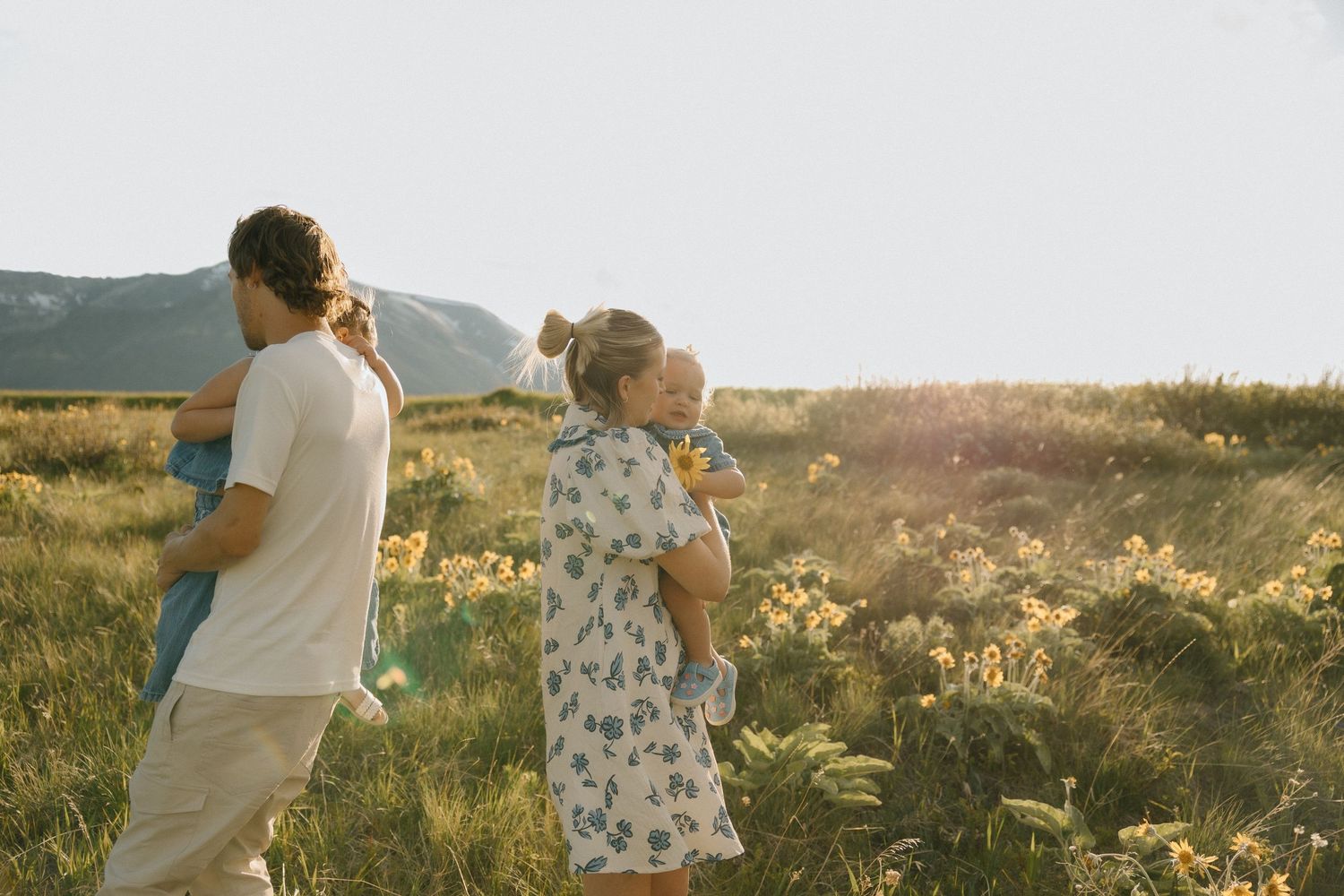 Couple walking through a golden meadow at sunset holding hands and enjoying the warm evening light.