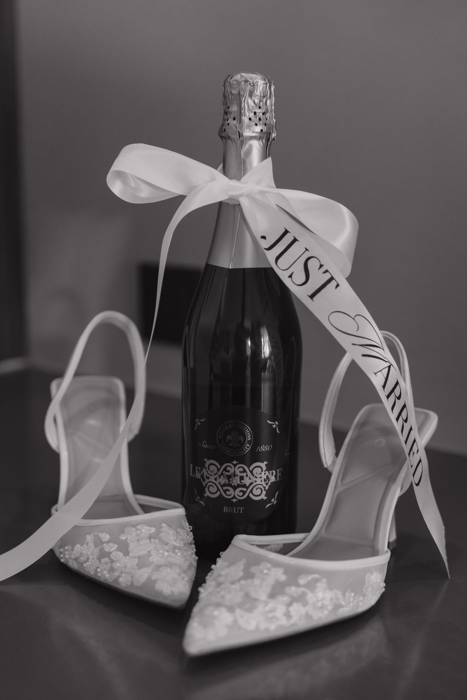 Wedding detail photo of bridal shoes and champagne bottle with Just Married ribbon at Majestic Elegance Costa Mujeres.