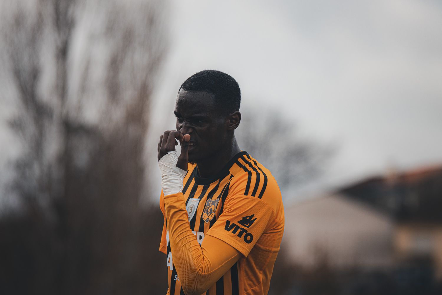 Players in yellow jerseys standing on a soccer field during an overcast day.