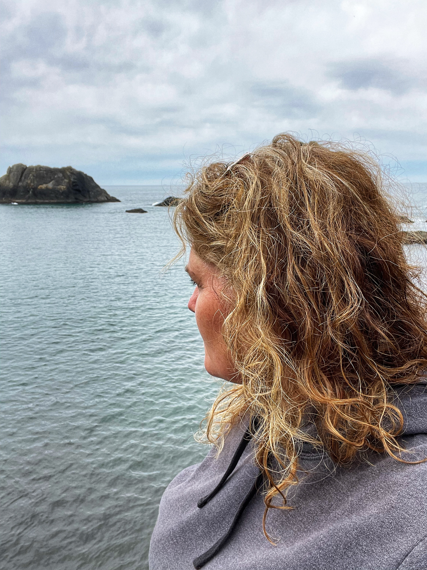 Serene ocean view with calm waters and distant islands on a cloudy day.