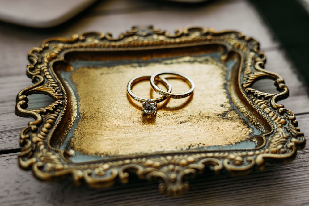 Gold vintage tray with wedding rings photographed in detail on wooden surface.