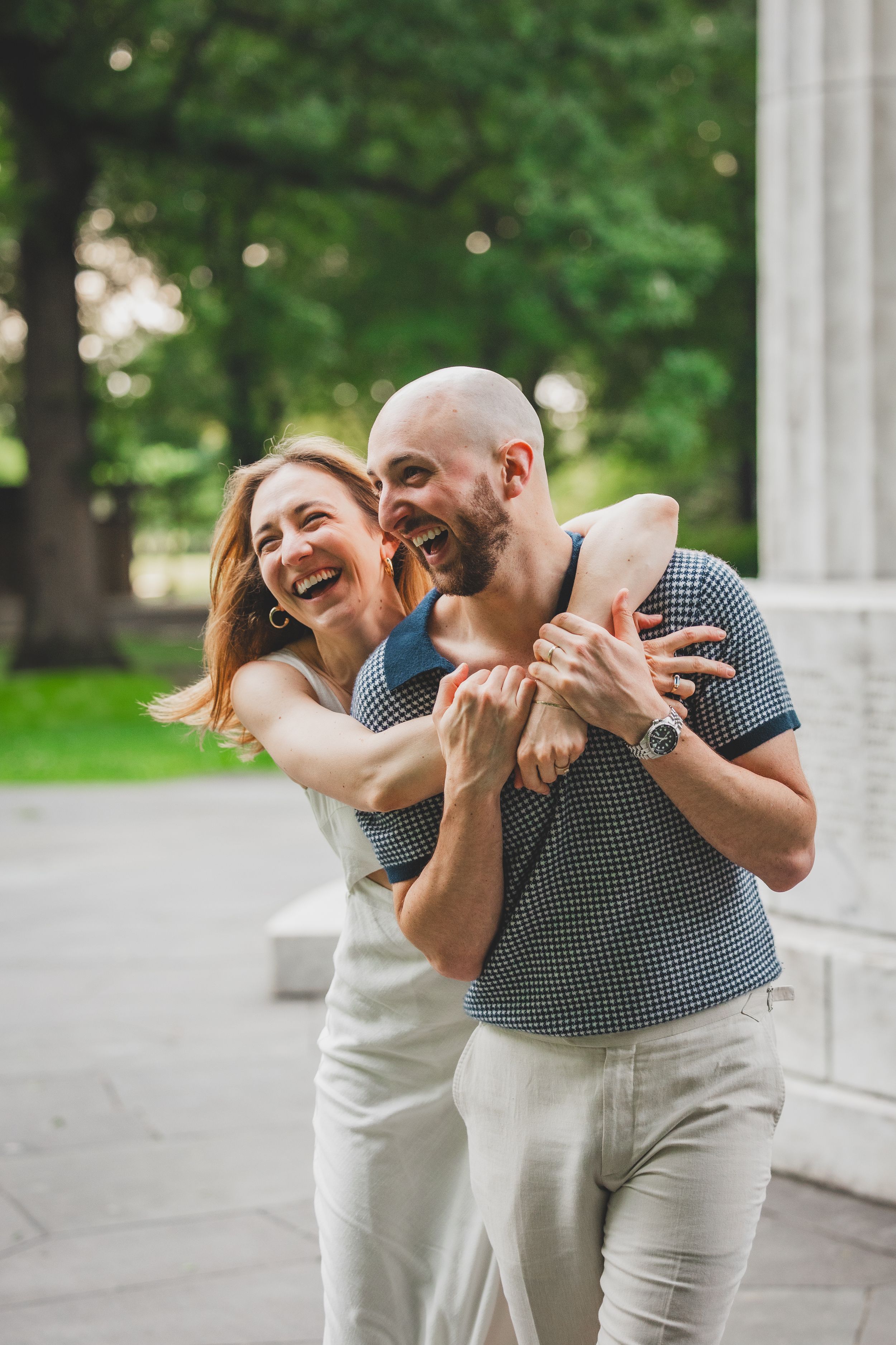 The couple laughing together in soft morning sunlight near the DC War Memorial