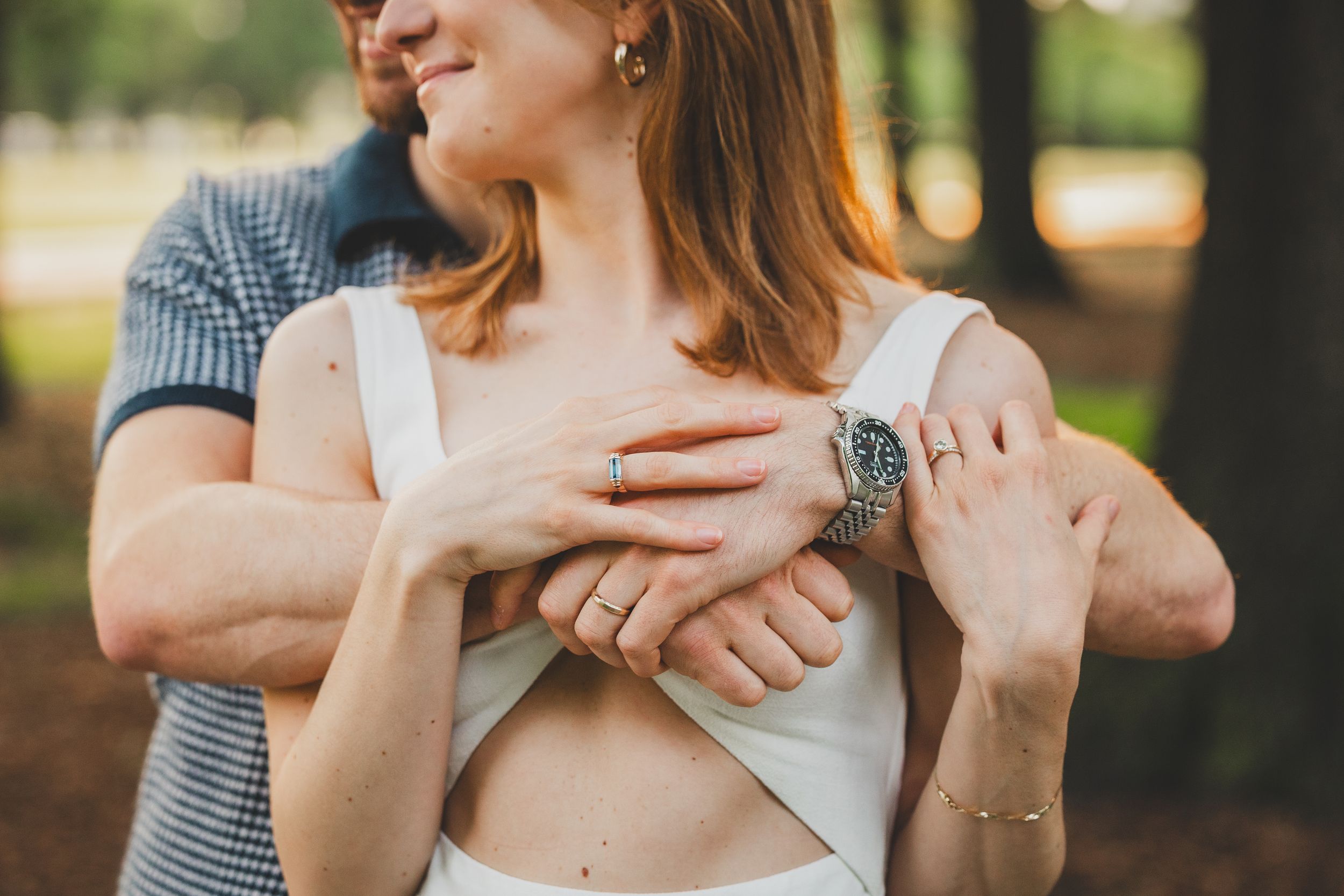 A couple embraces tenderly in a romantic outdoor photoshoot with soft natural lighting and blurred background.