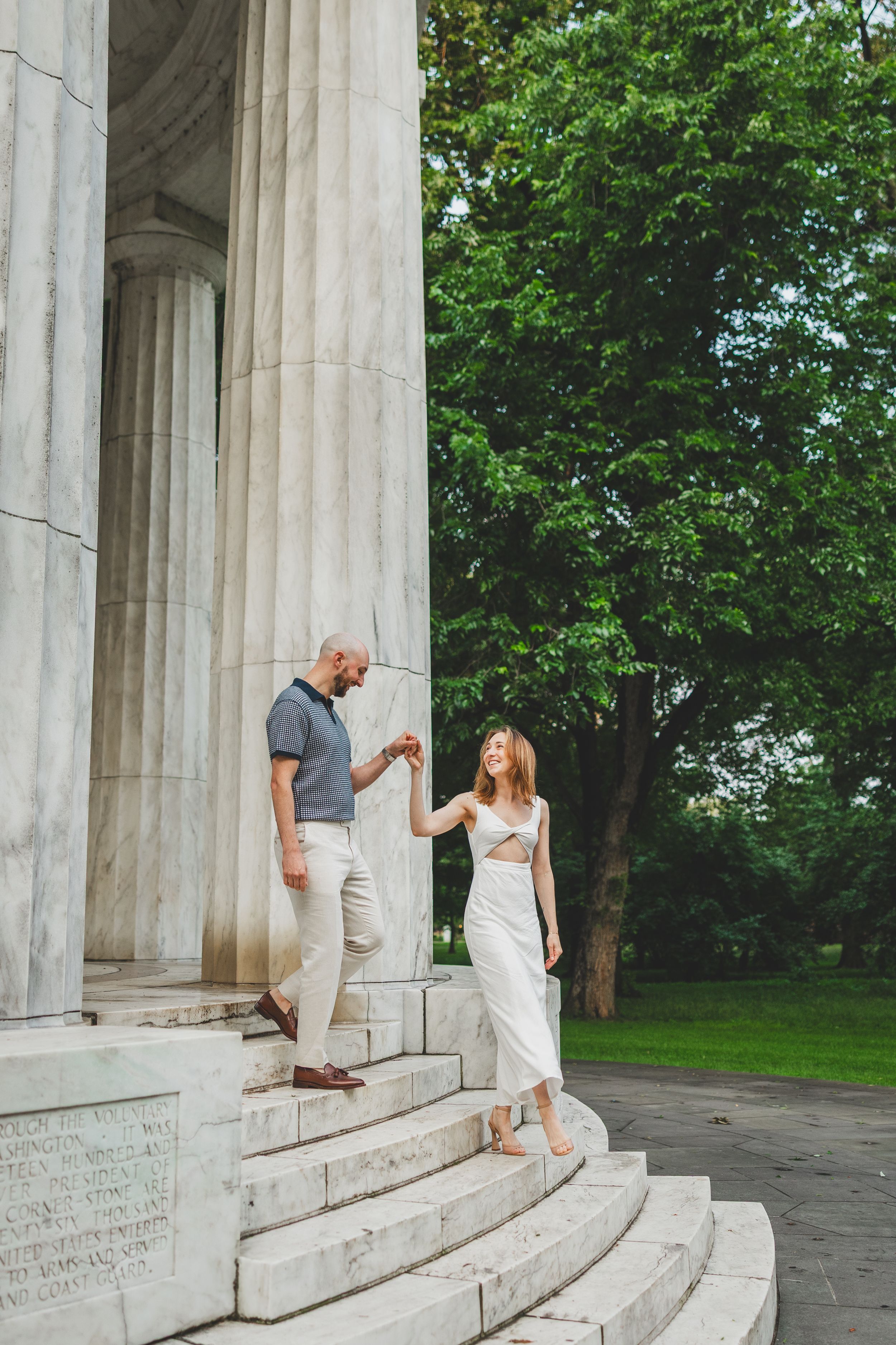 A couple poses playfully between classical stone columns in a series of romantic architectural shots.