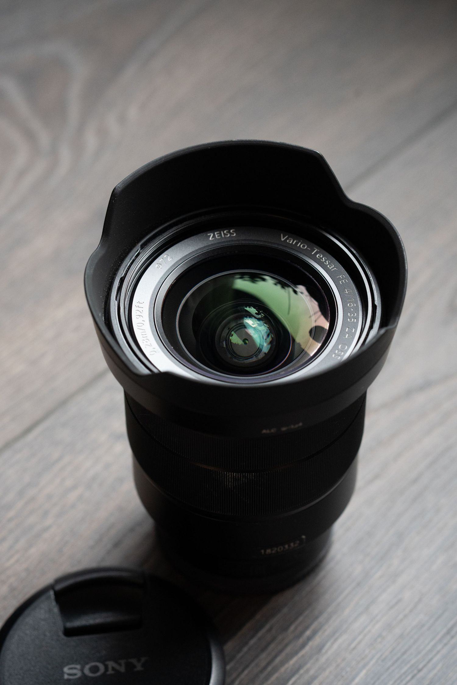 Close-up sequence of a black camera lens showing different angles and perspectives on a wooden surface.