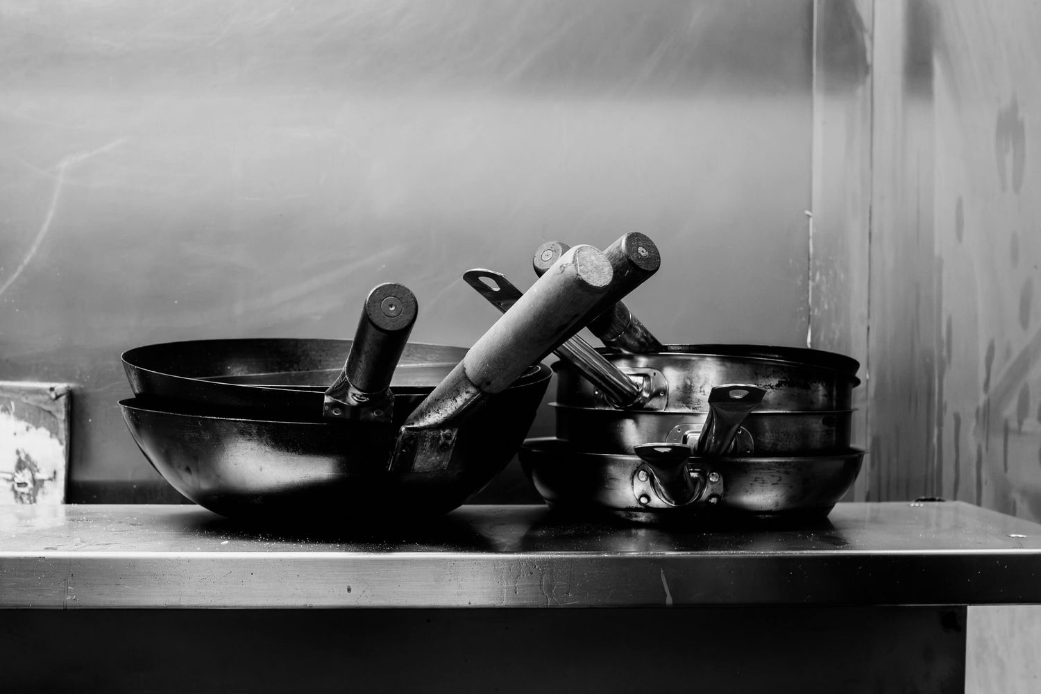 Black and white image of cooking pans and utensils arranged on a kitchen shelf.