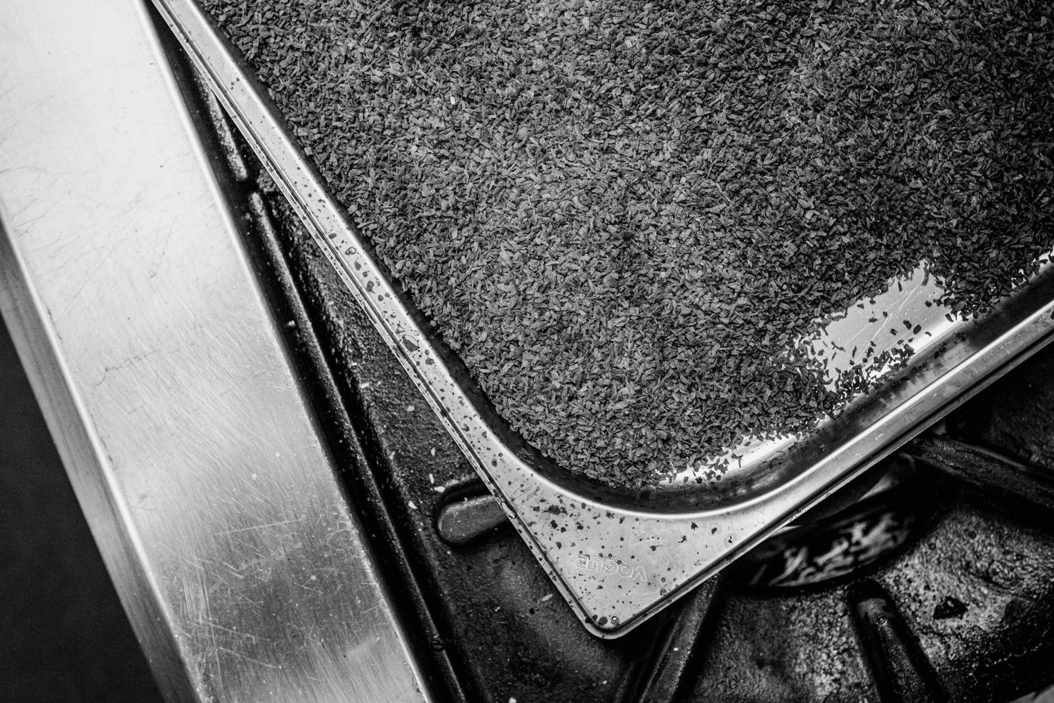 Close-up black and white detail of a worn leather seat corner showing texture and weathering.
