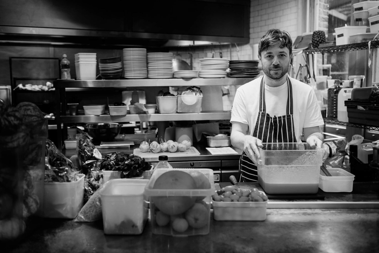 Professional chefs working in a busy commercial kitchen with stainless steel equipment and prep stations.