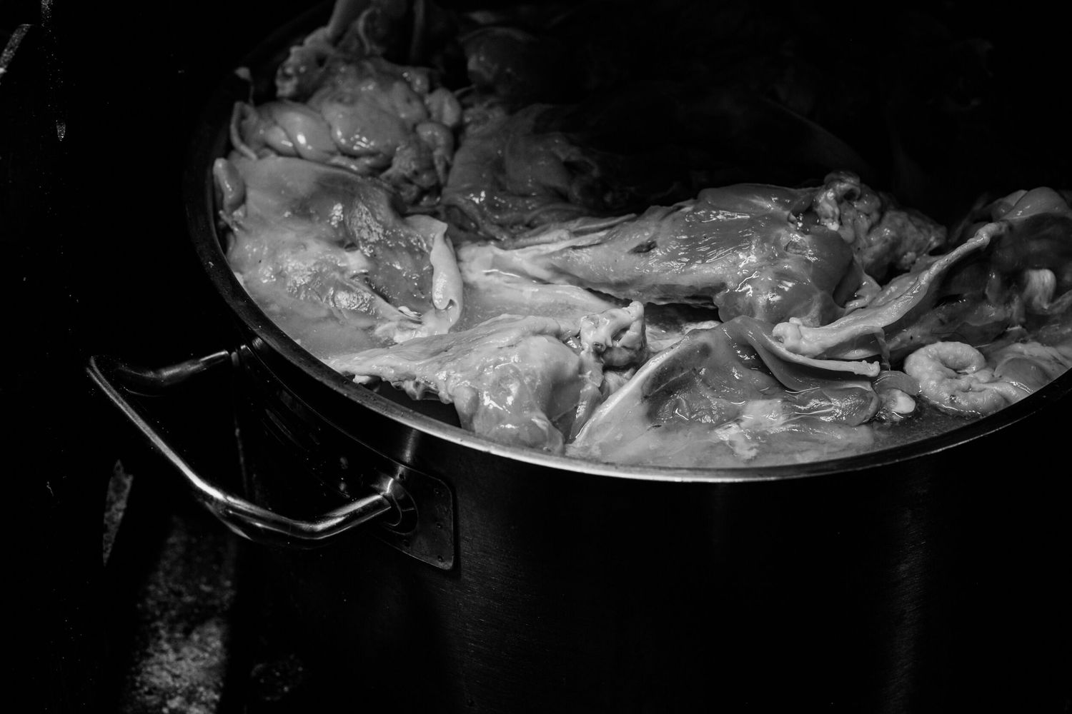 Fresh whole raw fish arranged on a dark surface with ice and garnishes for seafood preparation.
