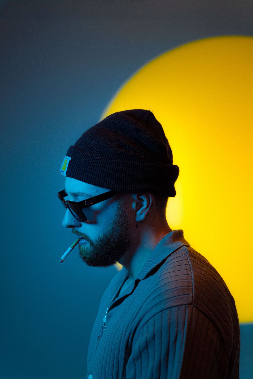 A silhouetted figure wearing a beanie is shown in profile against a vibrant yellow and blue background.