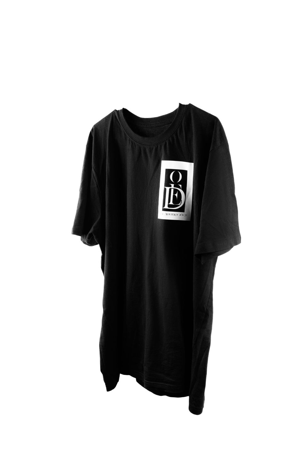 Three black t-shirts with small white square logo patches displayed on hangers against white background.