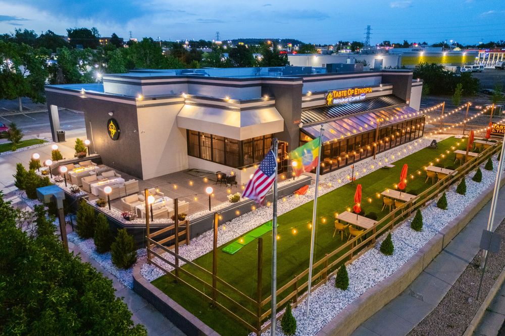 Aerial view of a modern outdoor dining area with string lights and multiple seating sections arranged in rows.