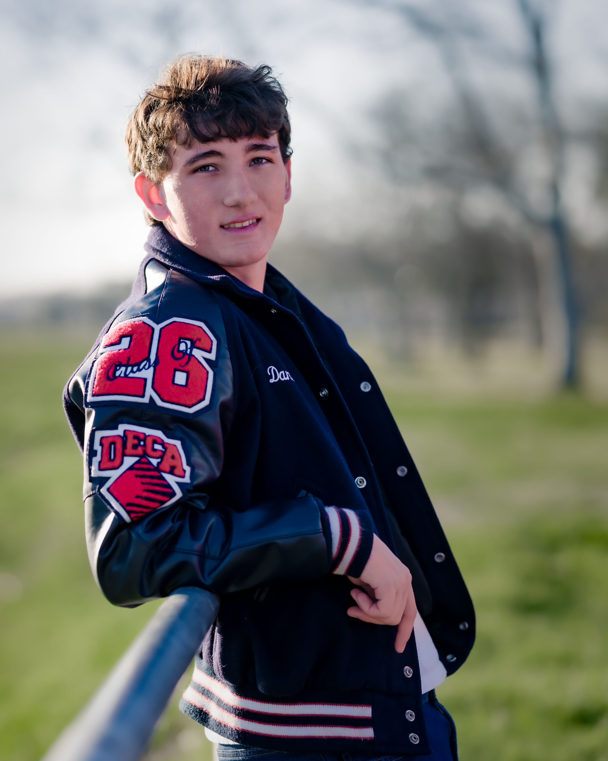 A varsity letterman jacket with red and white details shown in multiple angles on a cloudy day outdoors.