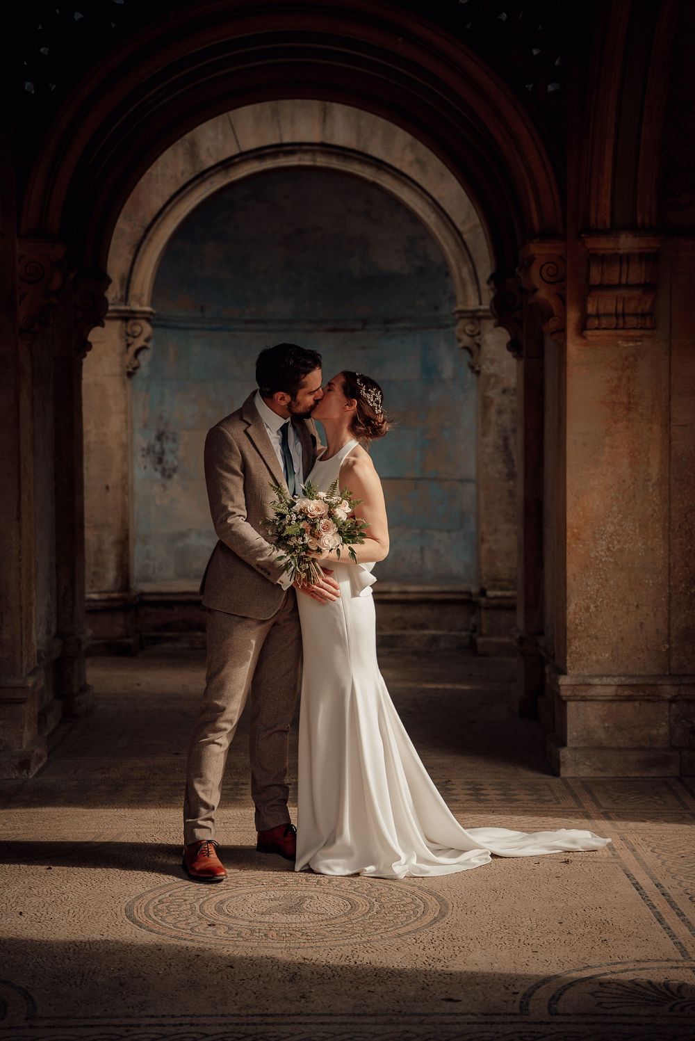 A romantic wedding photoshoot under stone archways with dramatic lighting.