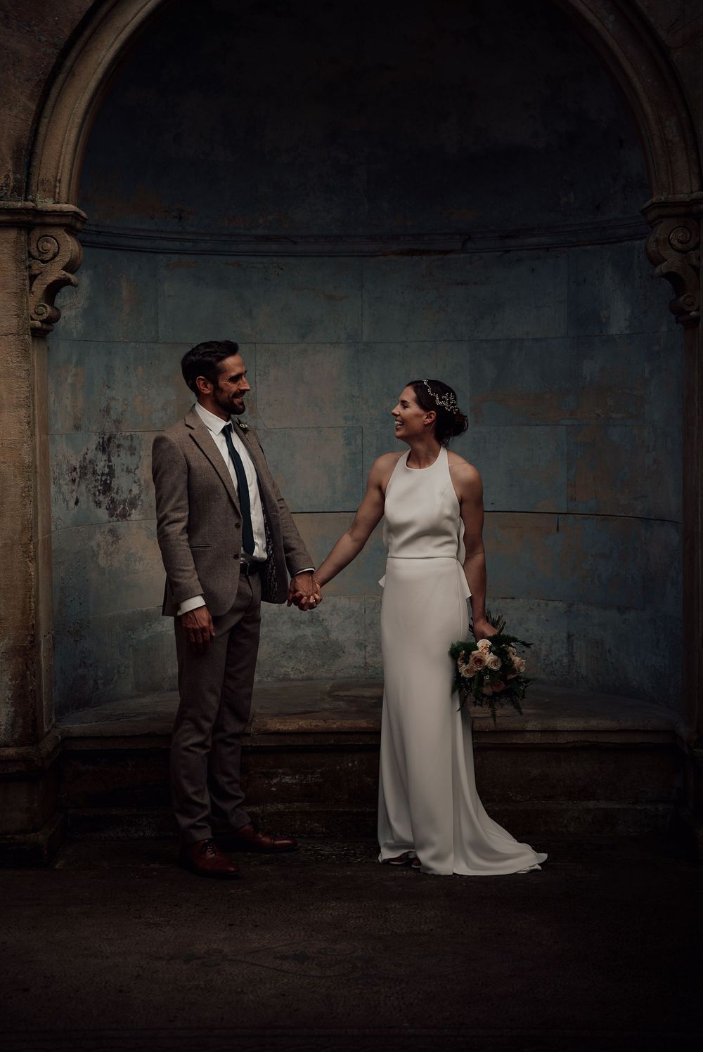 A couple shares playful moments during their wedding photoshoot in a rustic indoor setting.