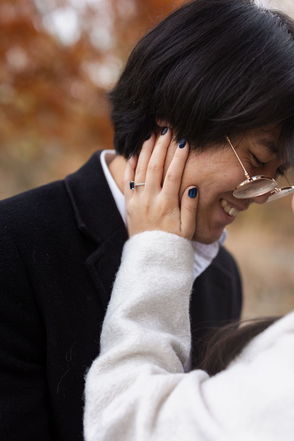 A couple shares an intimate moment against a blurred autumn background.