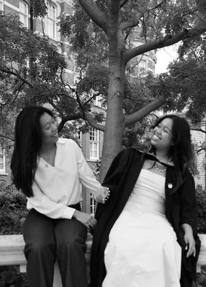 black and white photo of two sisters smiling at each other.
