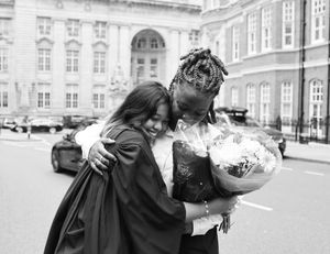 a photograph of a couple embracing, holding bouquets of flowers.