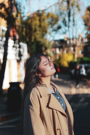 photograph of a woman tilting her face up to the sun, with her eyes closed.