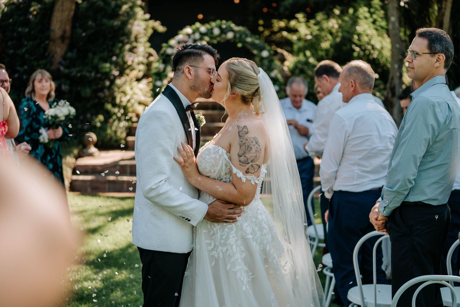 A couple shares their first dance at an outdoor wedding reception surrounded by guests.
