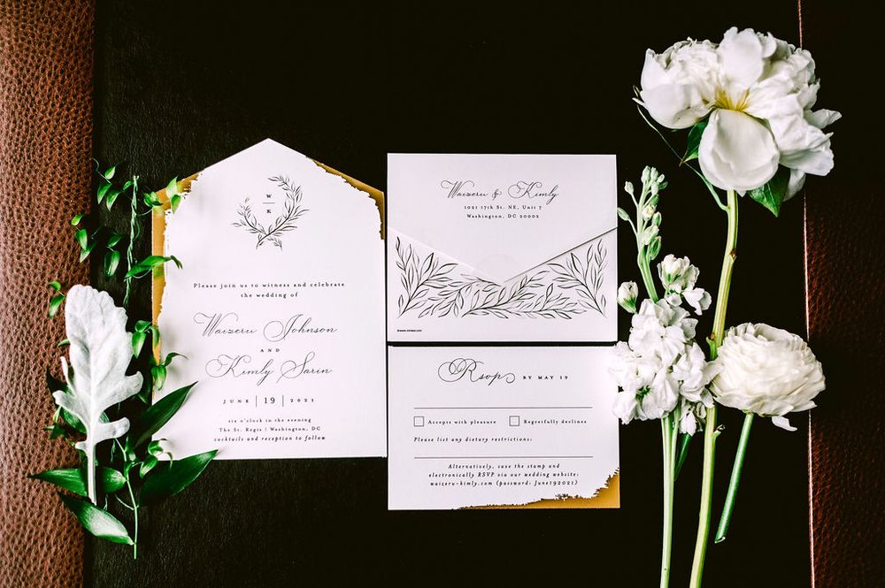 Elegant wedding invitations and stationery laid out with white flowers and delicate calligraphy details.
