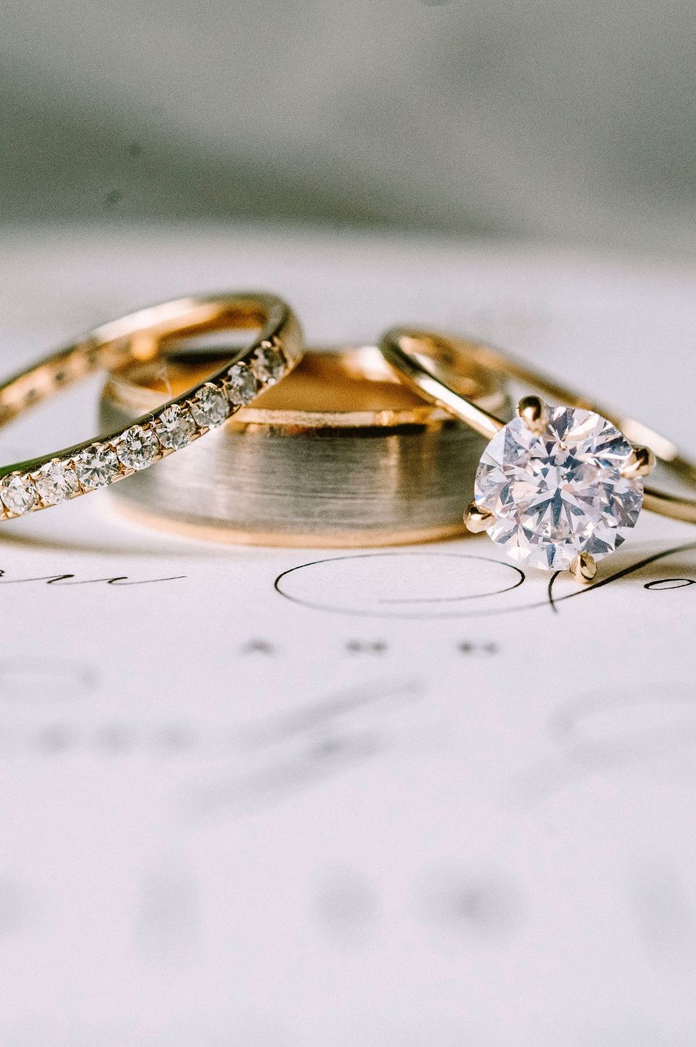 Close-up of gold wedding rings with diamonds on a white surface.