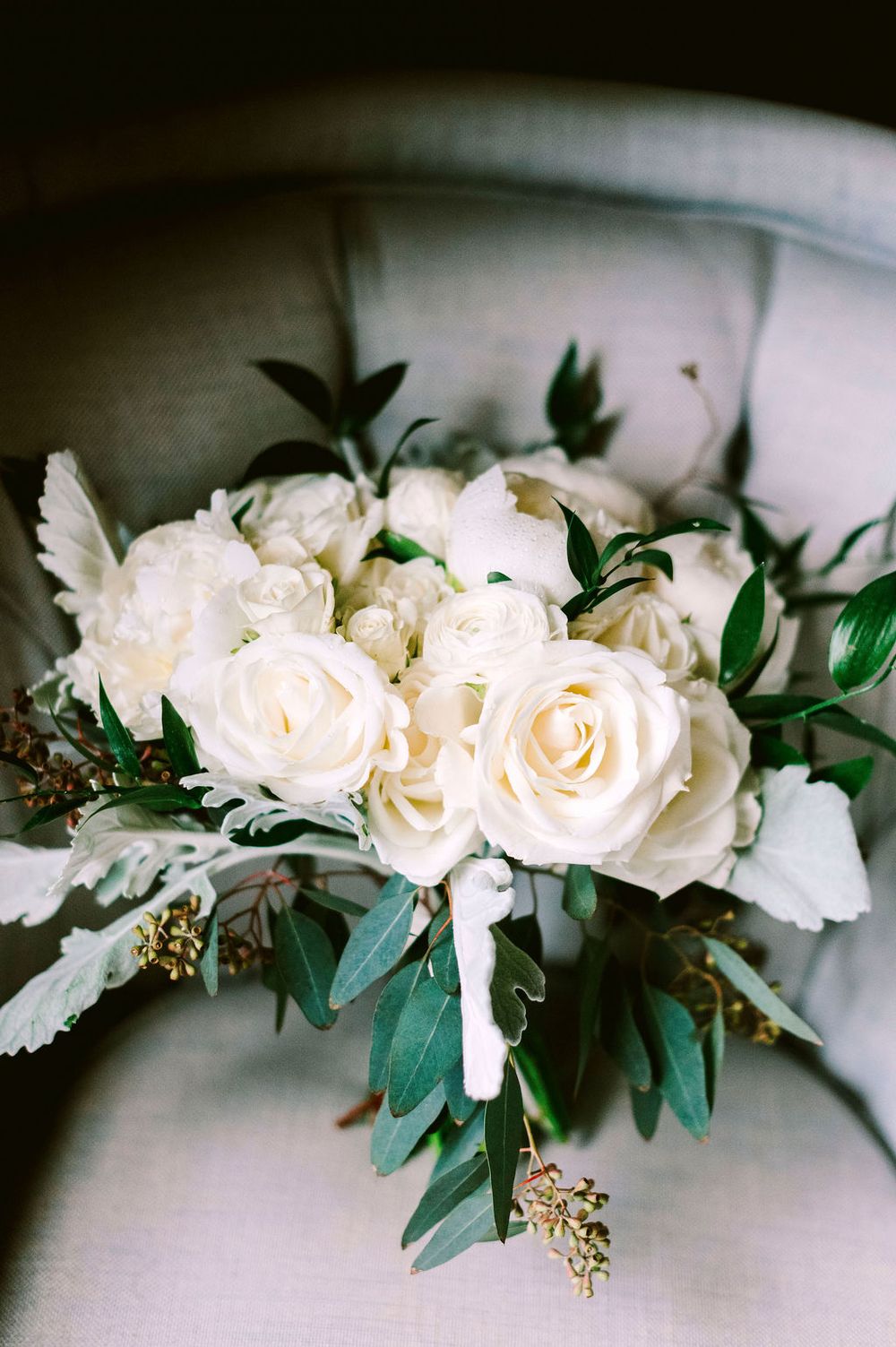White roses and greenery arranged in a romantic floral garland against a light background.