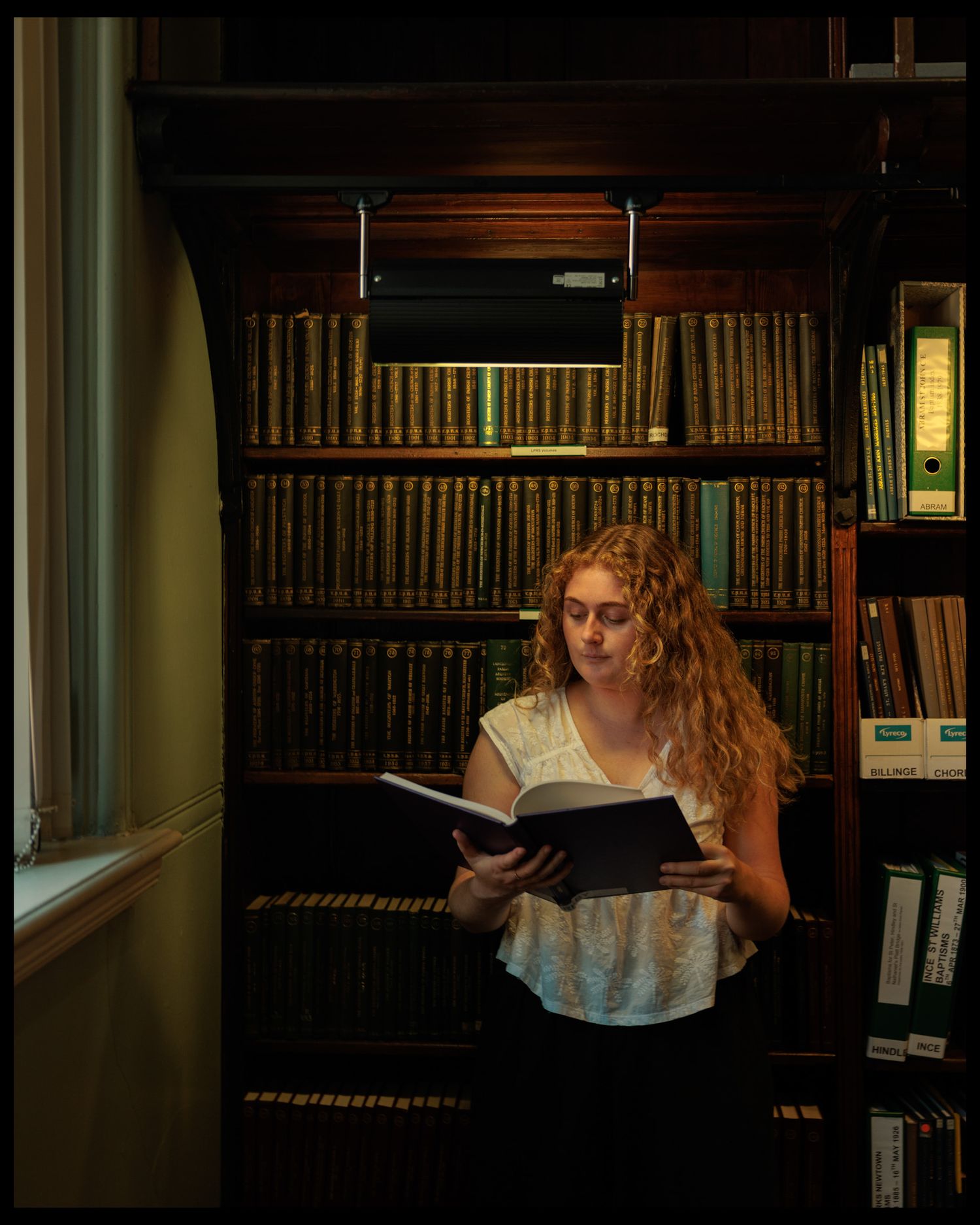 Reader exploring books in a traditional library with wooden shelving.