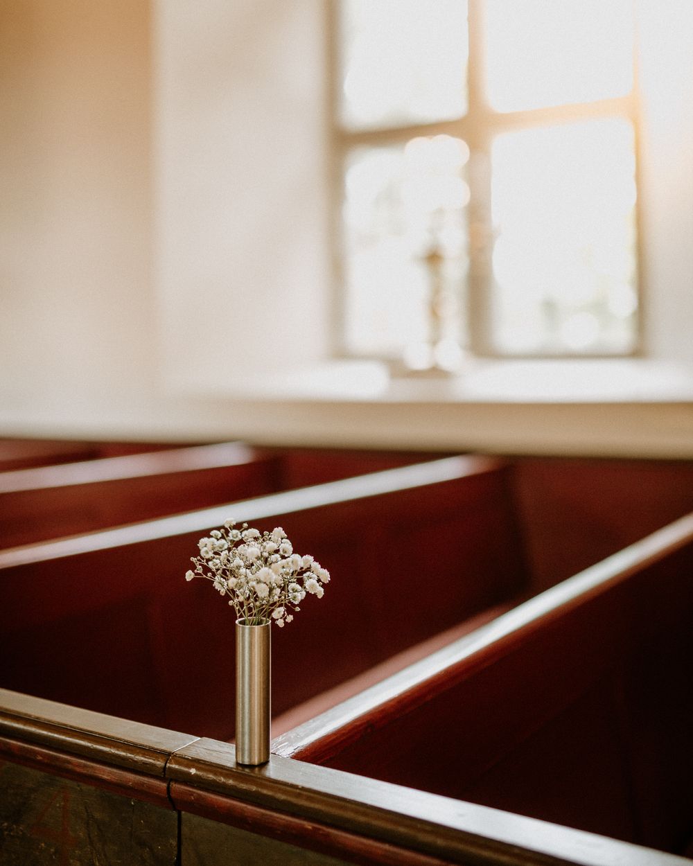 Blommor, sol i fönster och bänkar i solljus i Sandseryds kyrka, Jönköping.