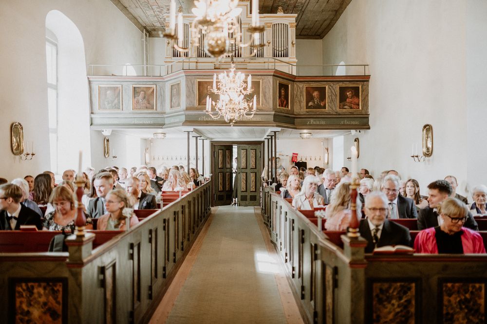 Gäster sitter i bänkarna i Sandseryds kyrka, under ett bröllop.