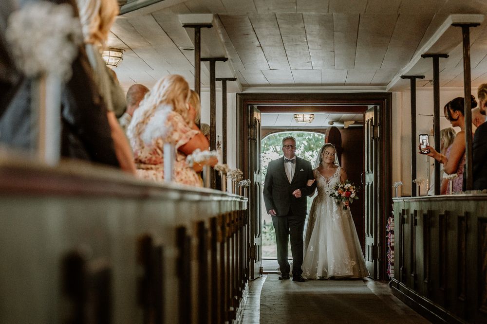 Brud och brudens far är på väg in genom dörren vid vigsel i Sandseryds kyrka.