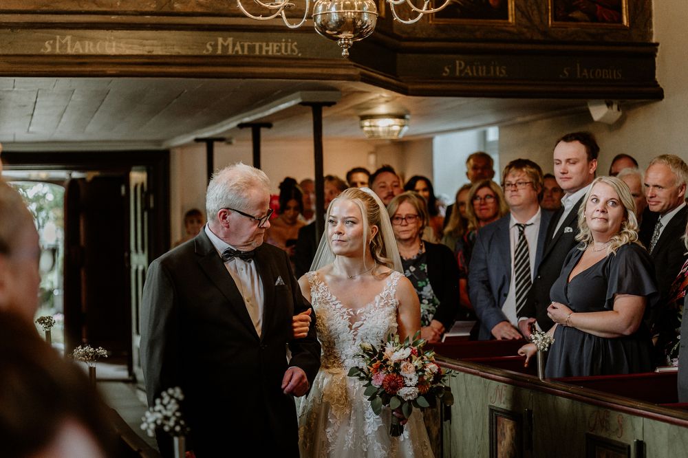 Brud och brudens far är på väg in genom dörren vid vigsel i Sandseryds kyrka.