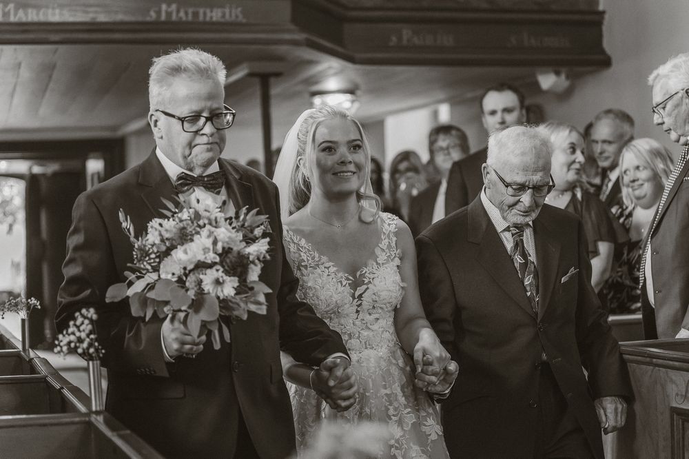 Brud och brudens far är på väg in genom dörren vid vigsel i Sandseryds kyrka. Bilden är svartvit.