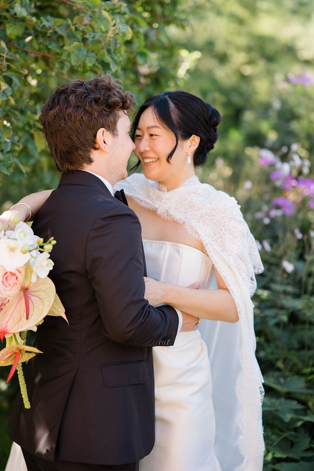 A romantic wedding moment captured in a garden setting with soft natural lighting and blooming flowers in the background.