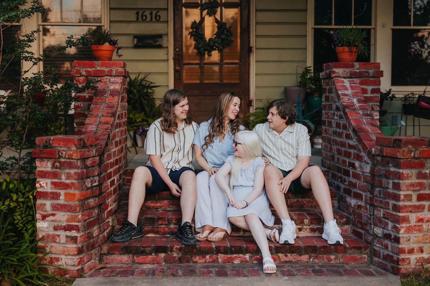 Three friends relaxing together on brick front porch steps of a vintage home.
