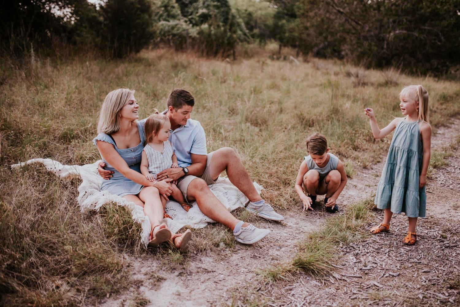Family session of Mother, Father, Youngest sitting on the blanket while the children explore in San Antonio, Texas.