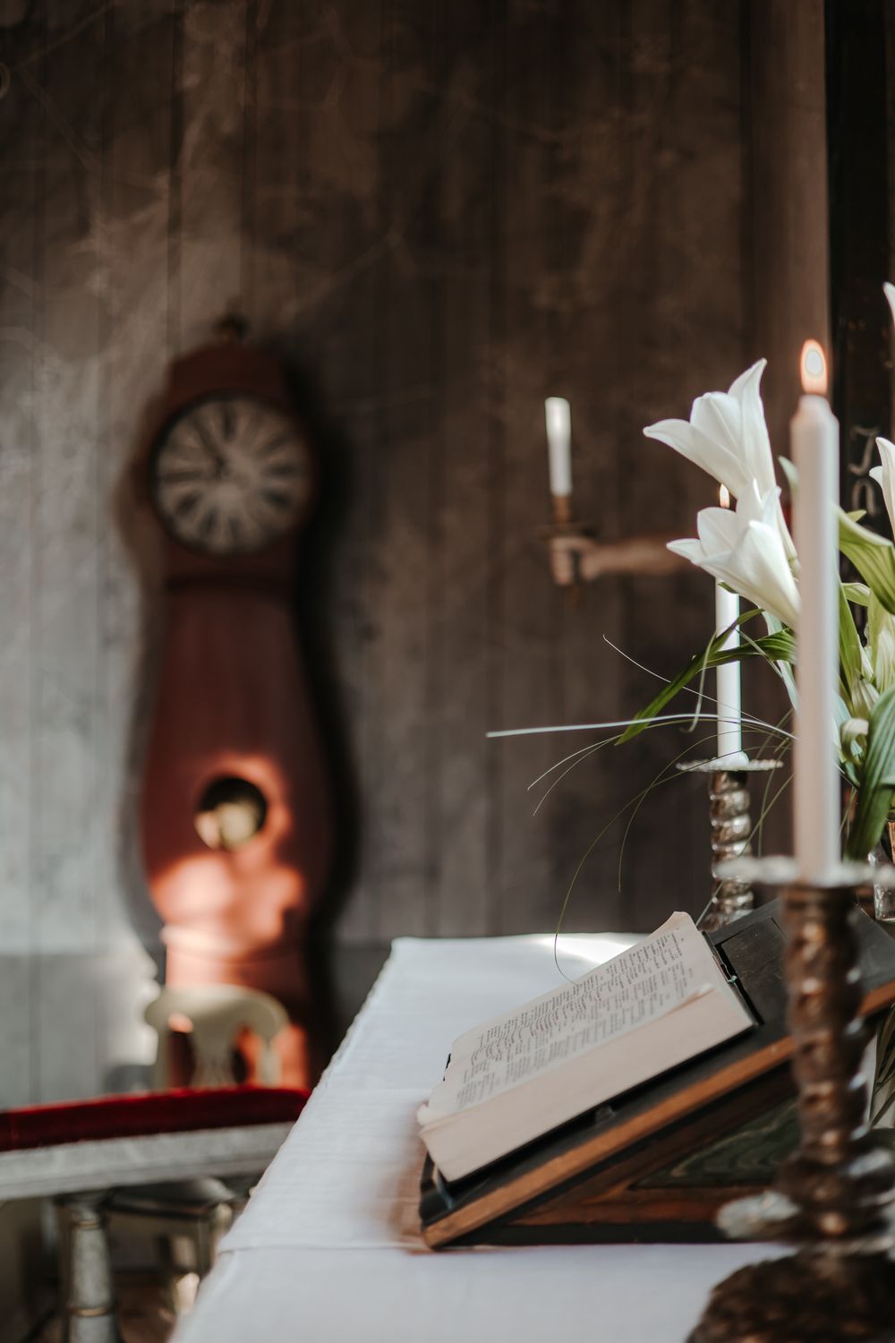 Open book with white lily flower on dark background with candlelight.