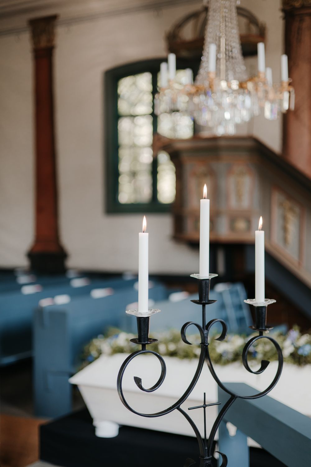 Black wrought iron candelabra with white taper candles creates an elegant table centerpiece at a formal event.