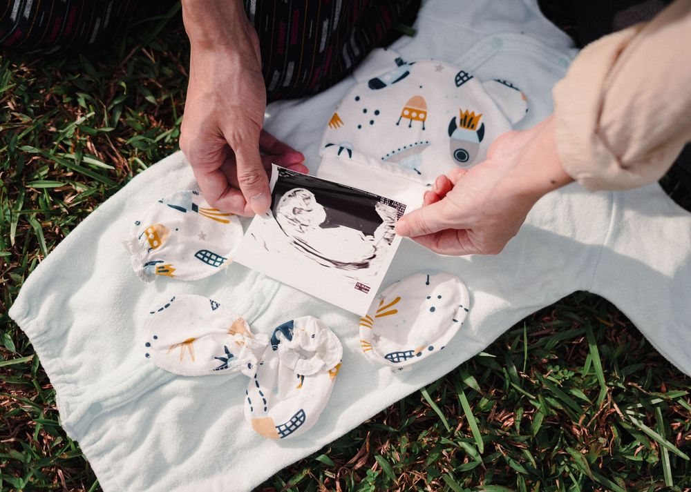 Someone holds a photo album or scrapbook on a white fabric with cute illustrated animal patterns in outdoor setting.