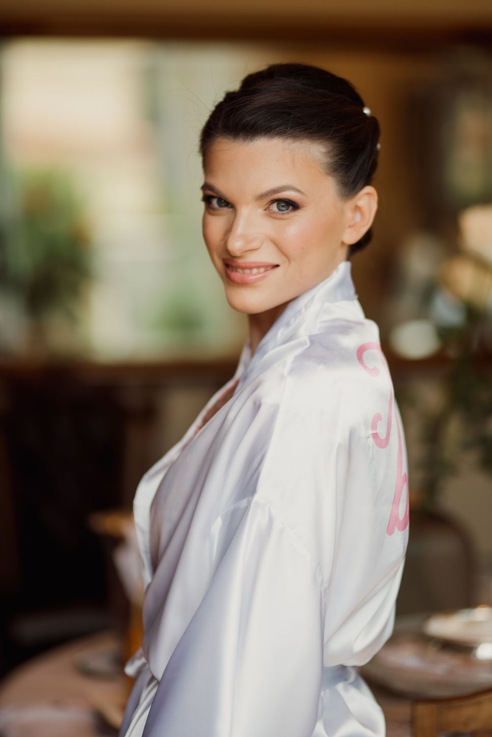 Side profile portrait of woman in white silk robe with elegant updo hairstyle.