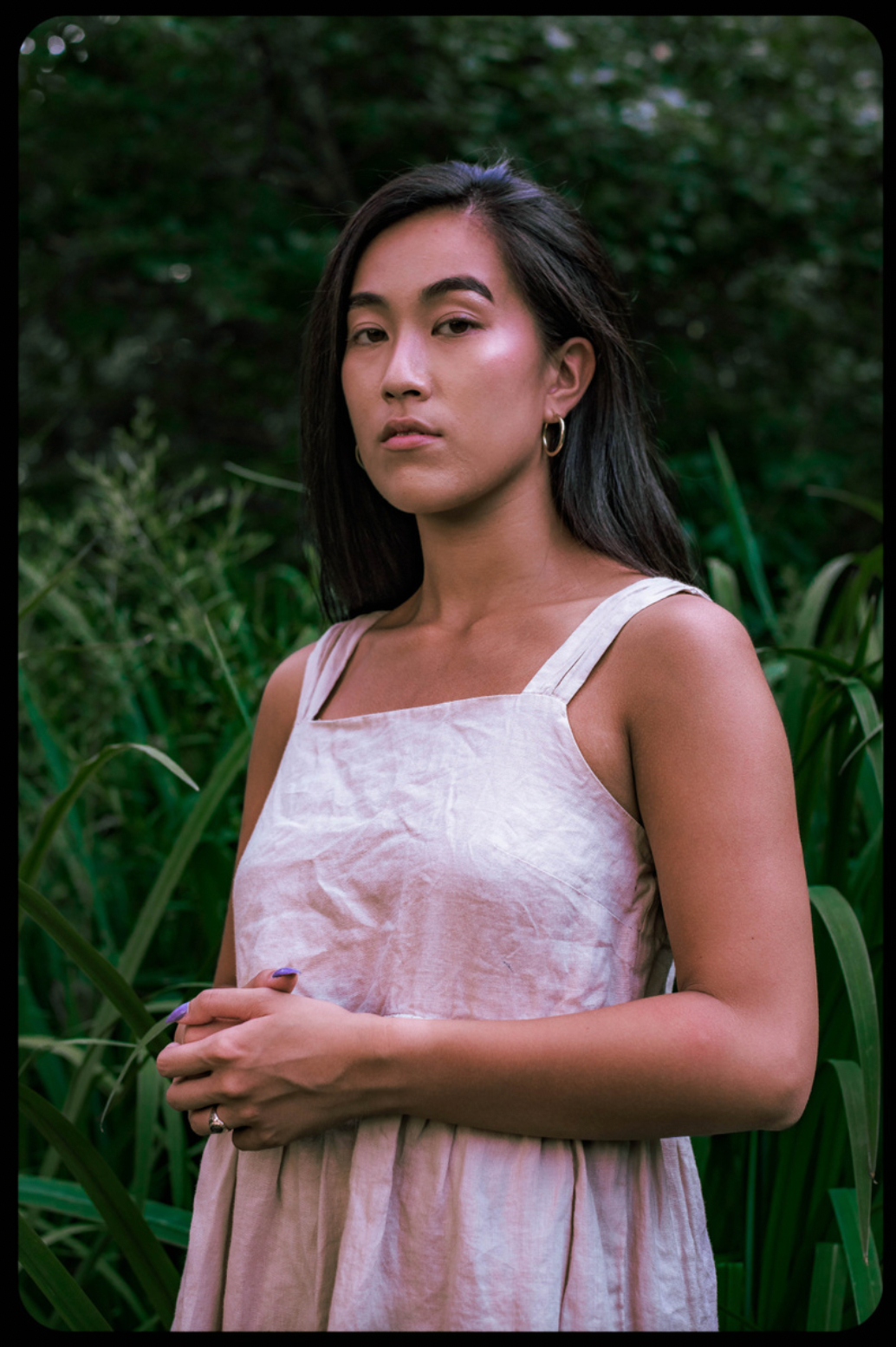 Portrait of person in pink dress standing among tall grass at golden hour.