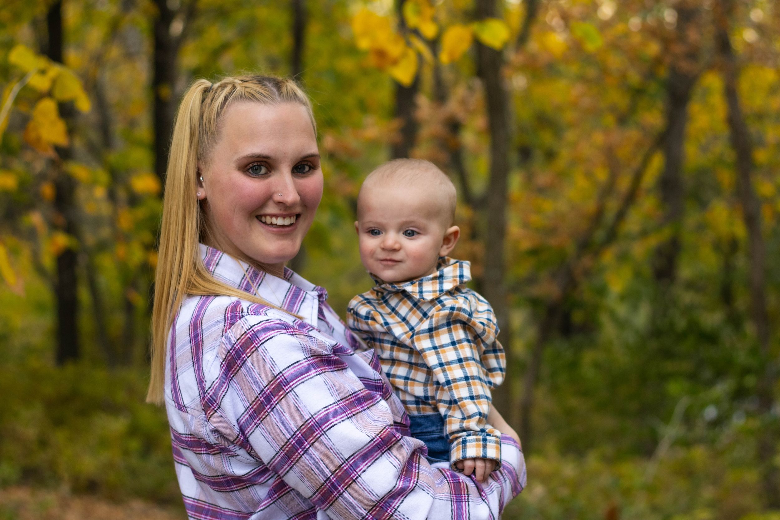 Family group poses together against backdrop of fall foliage.