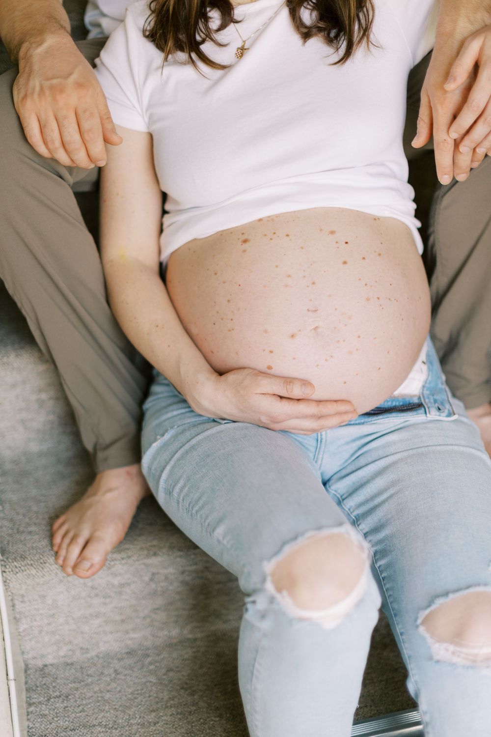 A close-up view of a pregnant belly with hands resting gently on the sides in Clifton, New Jersey.