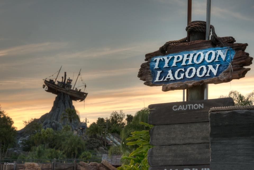 Illuminated Typhoon Lagoon sign and Mount Mayday silhouetted against a colorful sunset sky at Disney World water park.
