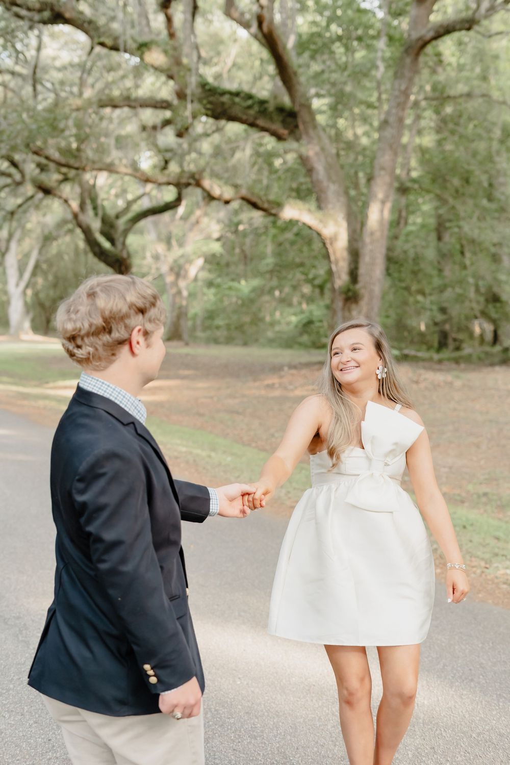 Young couple enjoying a romantic moment together on a tree-lined path in a dreamy outdoor setting.