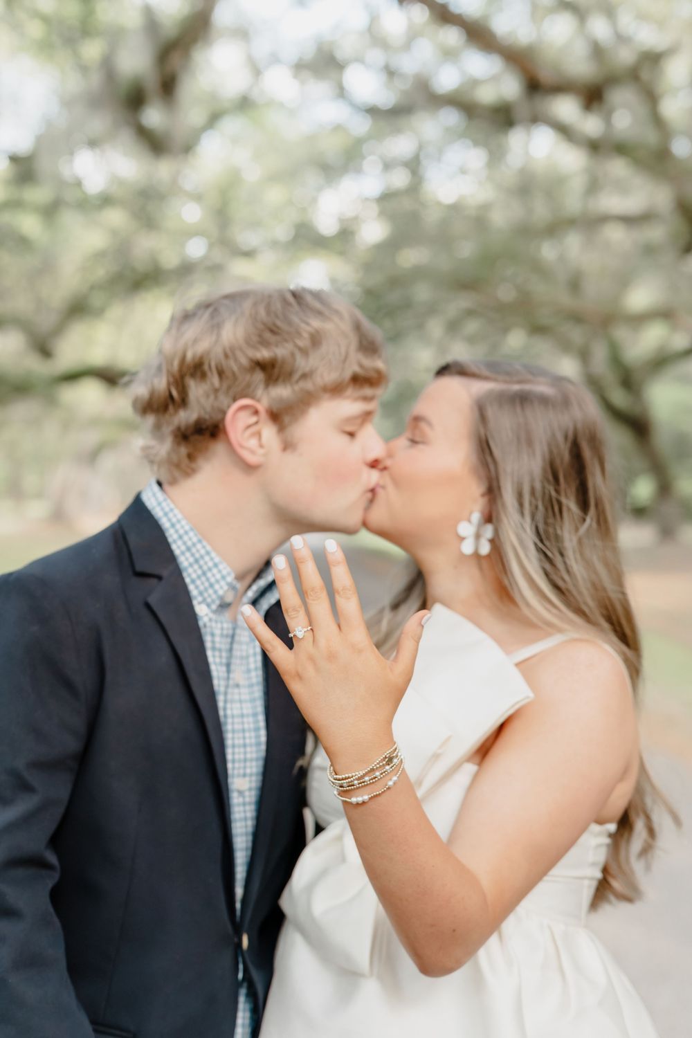 A sweet romantic engagement moment captured under oak trees with soft natural lighting.
