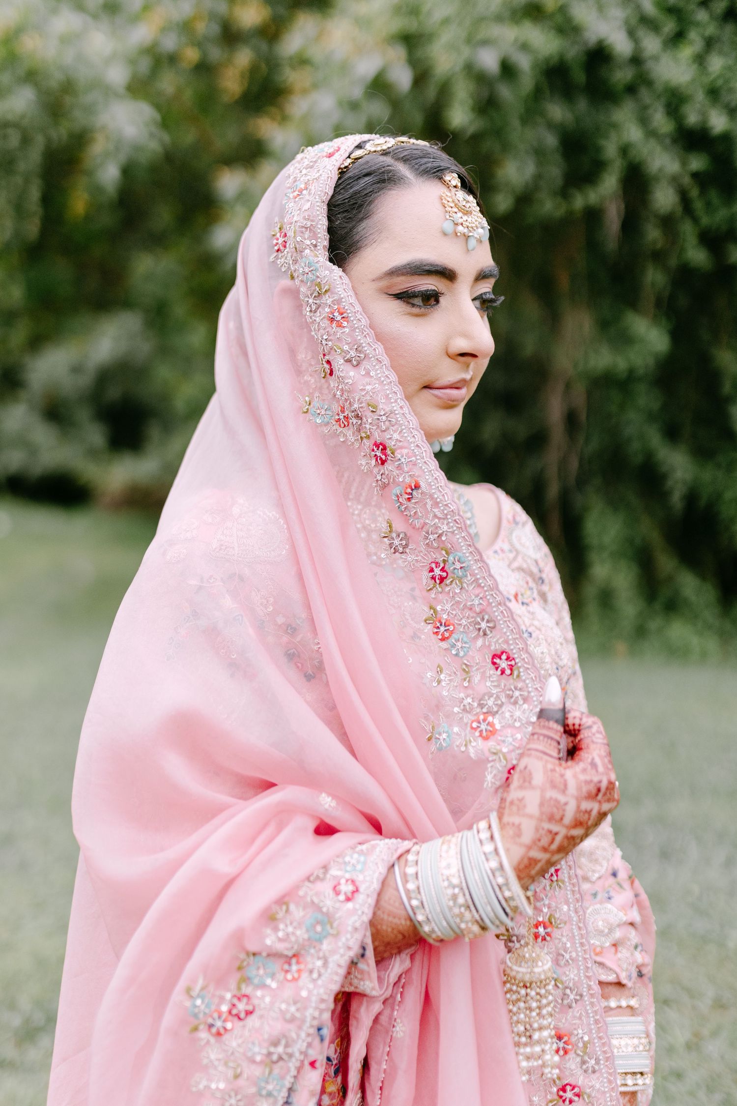 Pink embroidered dupatta with intricate floral details and traditional South Asian bridal jewelry.