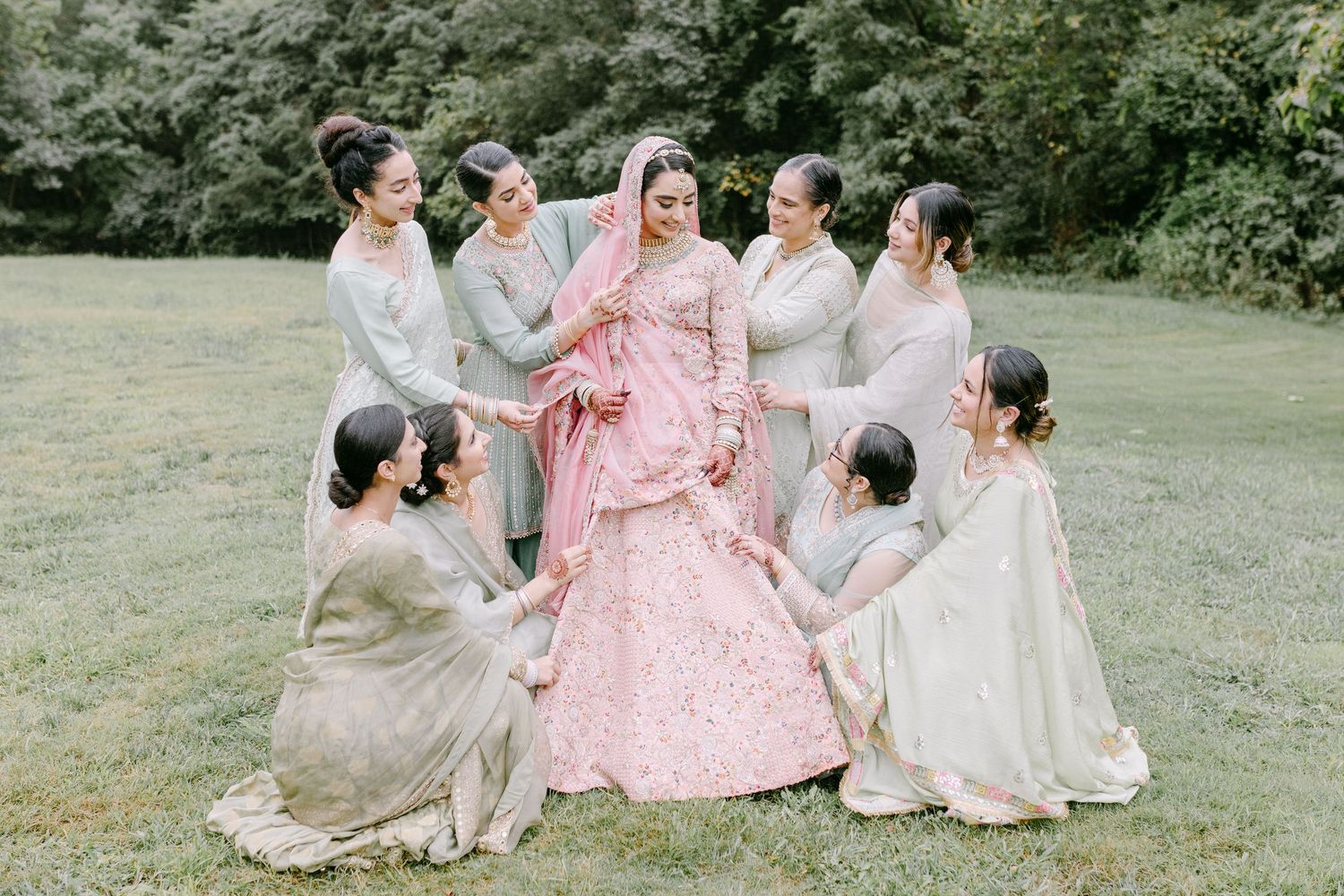 Wedding party in coordinated outfits gathering on green lawn.